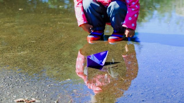 photo of a paper boat in a puddle